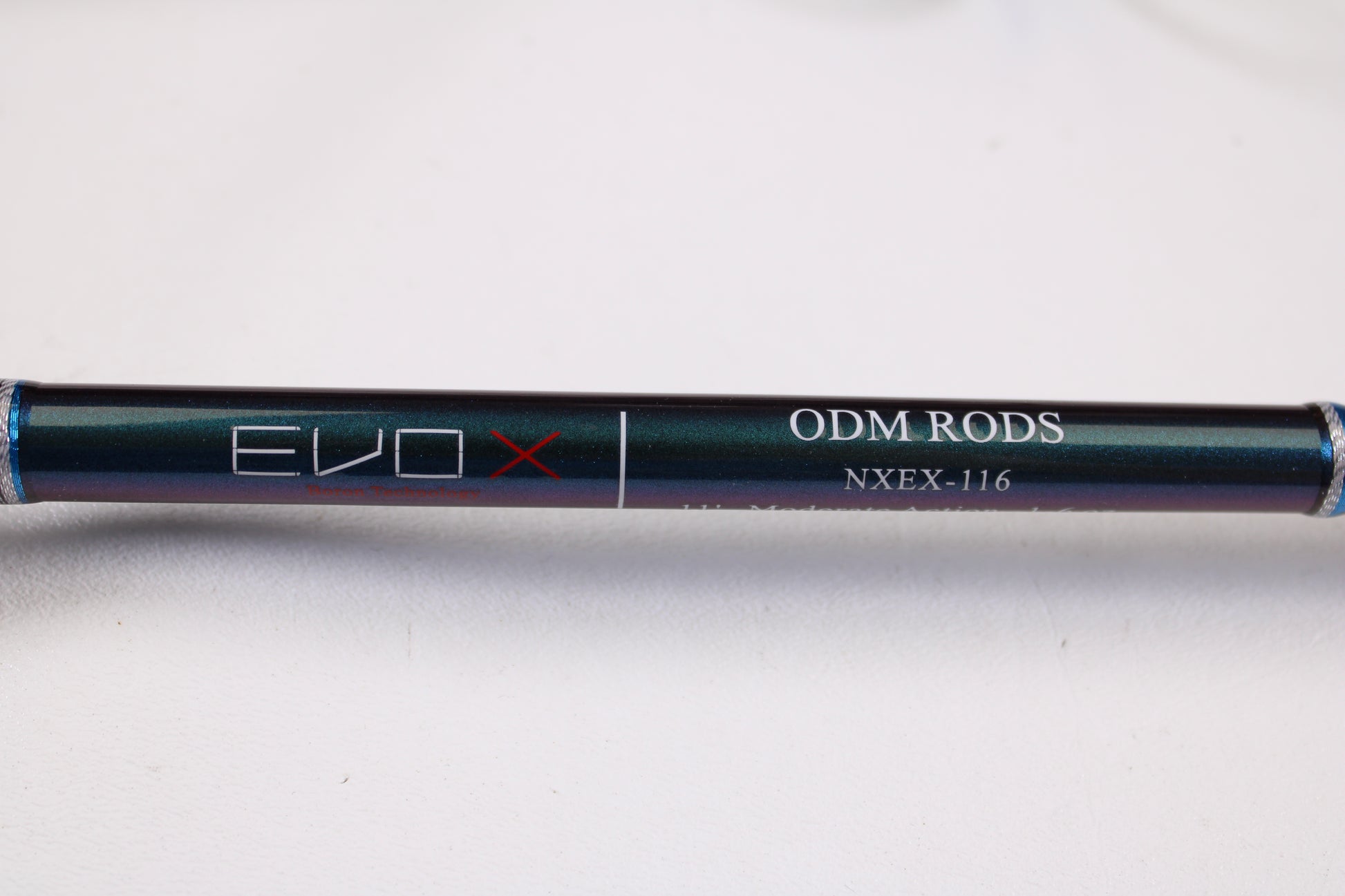 A close-up of the ODM Rods EVO X NXEX-116 11'0" 2pc Used Spinning Rod in excellent condition on a light surface, perfect for those interested in quality used gear or the Rod and Reel Trade-In Program for store credit.