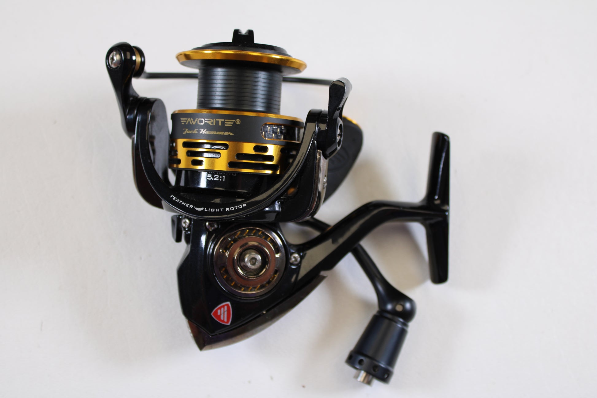 A close-up of a Favorite Jack Hammer JHM2500 5.2:1 used spinning reel in excellent condition, featuring black and gold metallic details and handle, set against a white background—ideal for anglers exploring our rod and reel trade-in program.