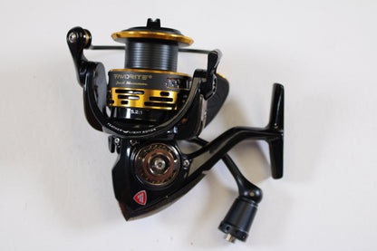 A close-up of a Favorite Jack Hammer JHM2500 5.2:1 used spinning reel in excellent condition, featuring black and gold metallic details and handle, set against a white background—ideal for anglers exploring our rod and reel trade-in program.