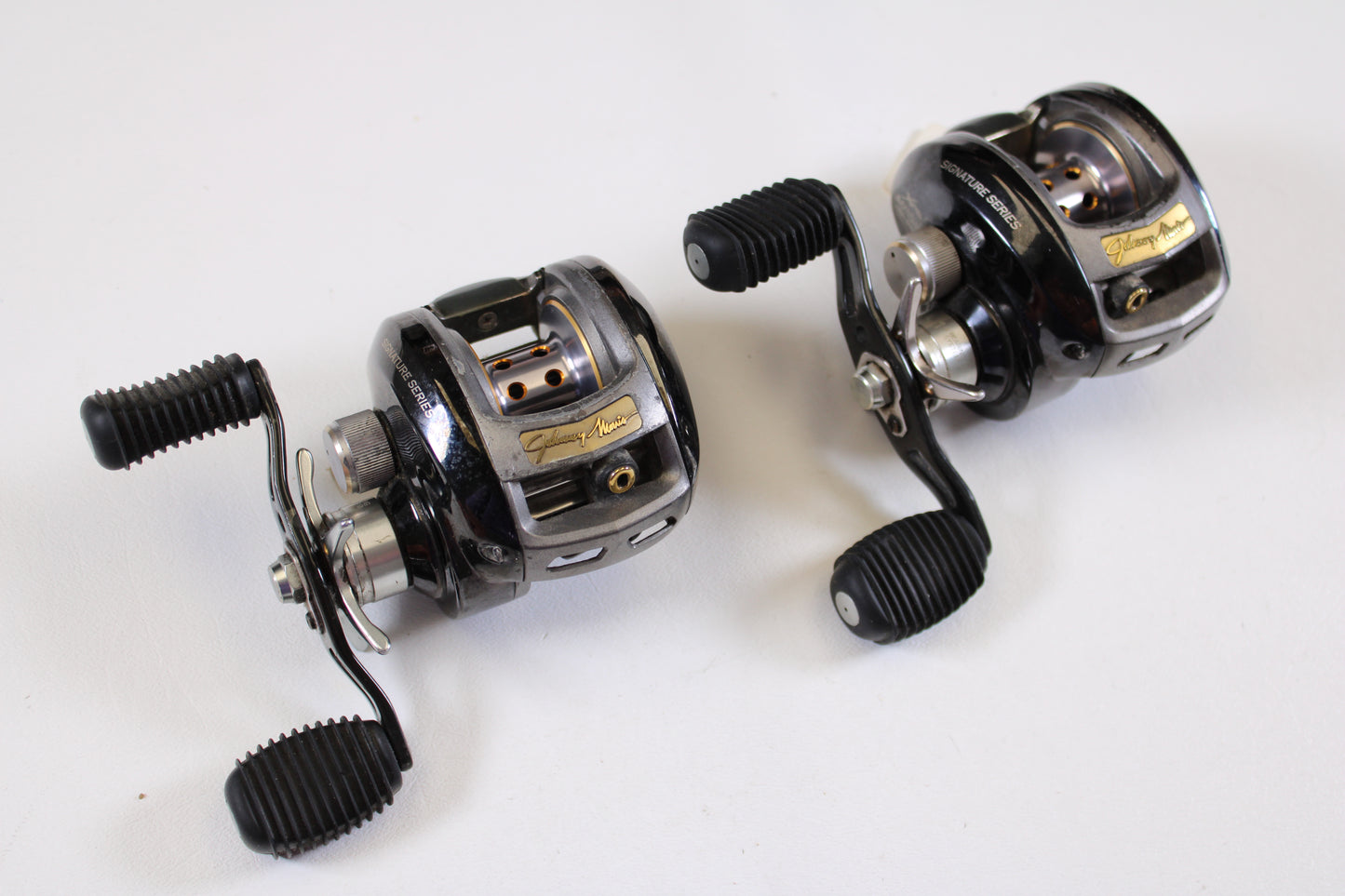 Two used Bass Pro Shops Johnny Morris JMX10HD 6.4:1 RH casting reels, qty 2, in good condition with dual handles and ribbed grips; ideal for trade-in or store credit.