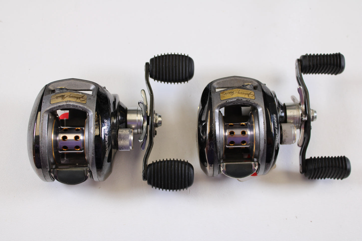 Two used Bass Pro Shops Johnny Morris JMX10HD 6.4:1 RH casting reels (Qty: 2, good condition) are displayed side by side—ideal for upgrading your fishing gear through our rod and reel trade-in program.