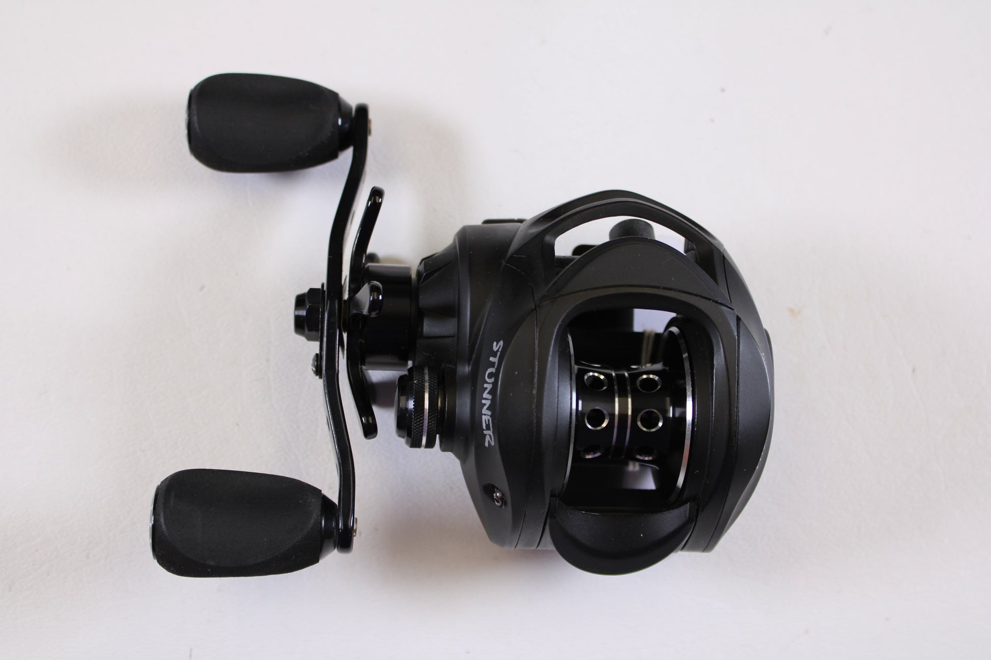 A Fitzgerald Stunner 6.3:1 LH used baitcasting reel in excellent condition, black with two handles, is shown from above on a white background—the word "STUNNER" displayed on the side, ideal for anglers seeking quality used gear.