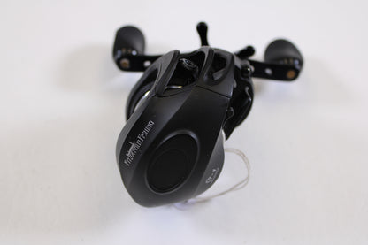 A used Fitzgerald Stunner 6.3:1 LH casting reel in excellent condition, with “PCASTING FISHING” on its side, sits on a white surface. This compact black reel with dual handles is perfect for rod and reel trade-in upgrades.