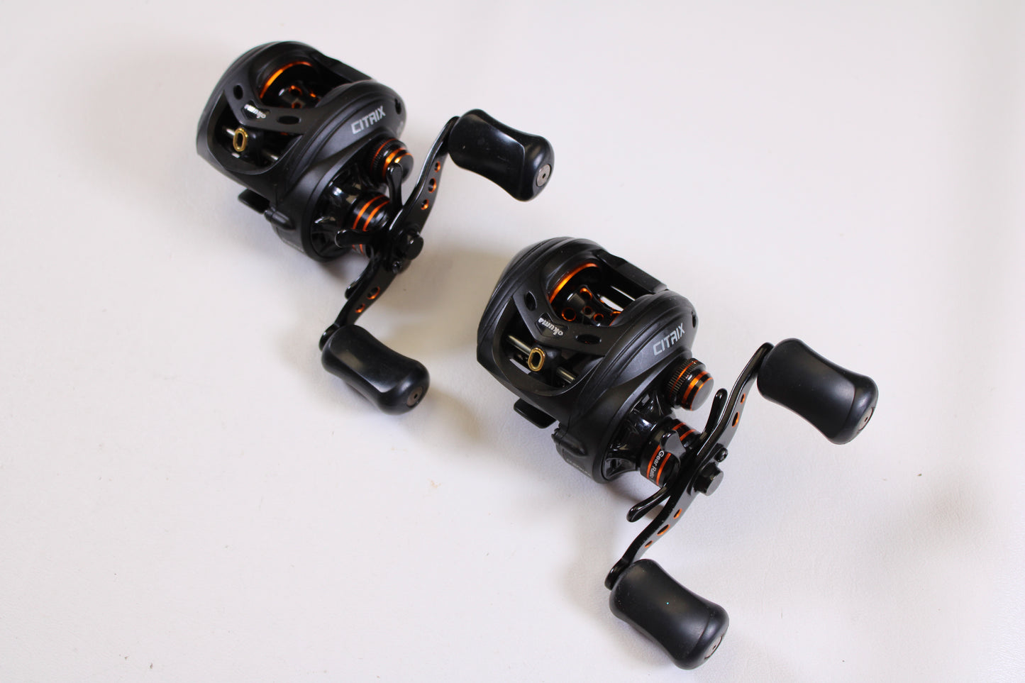 Two Okuma Citrix Ci-273LXa 7.3:1 LH used baitcasting reels (Qty: 2, very good condition) are displayed diagonally on a white surface—an excellent choice for upgrading through our rod and reel trade-in program.