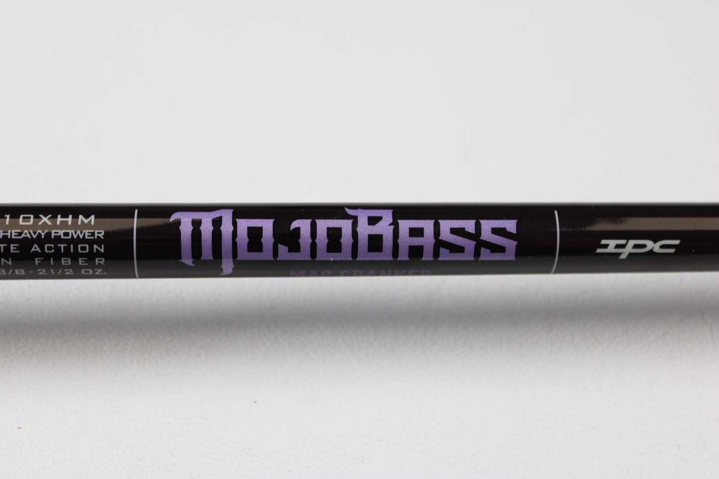 Close-up of a black St. Croix Mojo Bass JOC710XHM Mag Cranker 7'10" XH used casting rod in mint condition, featuring purple "Mojo Bass" text and symbols on white background. Trade in your gear for store credit through our Rod and Reel Trade-In Program.