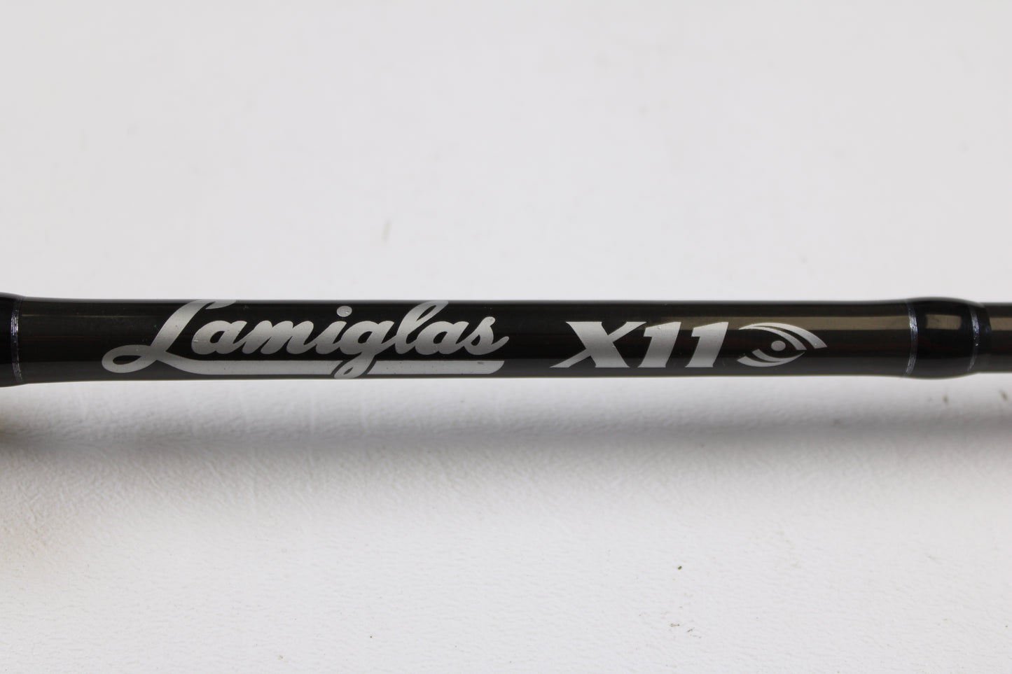 A close-up of a Lamiglas X11 Graphite Handle LX86MCGH 8'6" Medium 2 Piece Used Casting Rod in excellent condition, featuring the Lamiglas brand and model name in white lettering, displayed against a plain white background.