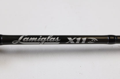 A close-up of a Lamiglas X11 Graphite Handle LX86MCGH 8'6" Medium 2 Piece Used Casting Rod in excellent condition, featuring the Lamiglas brand and model name in white lettering, displayed against a plain white background.