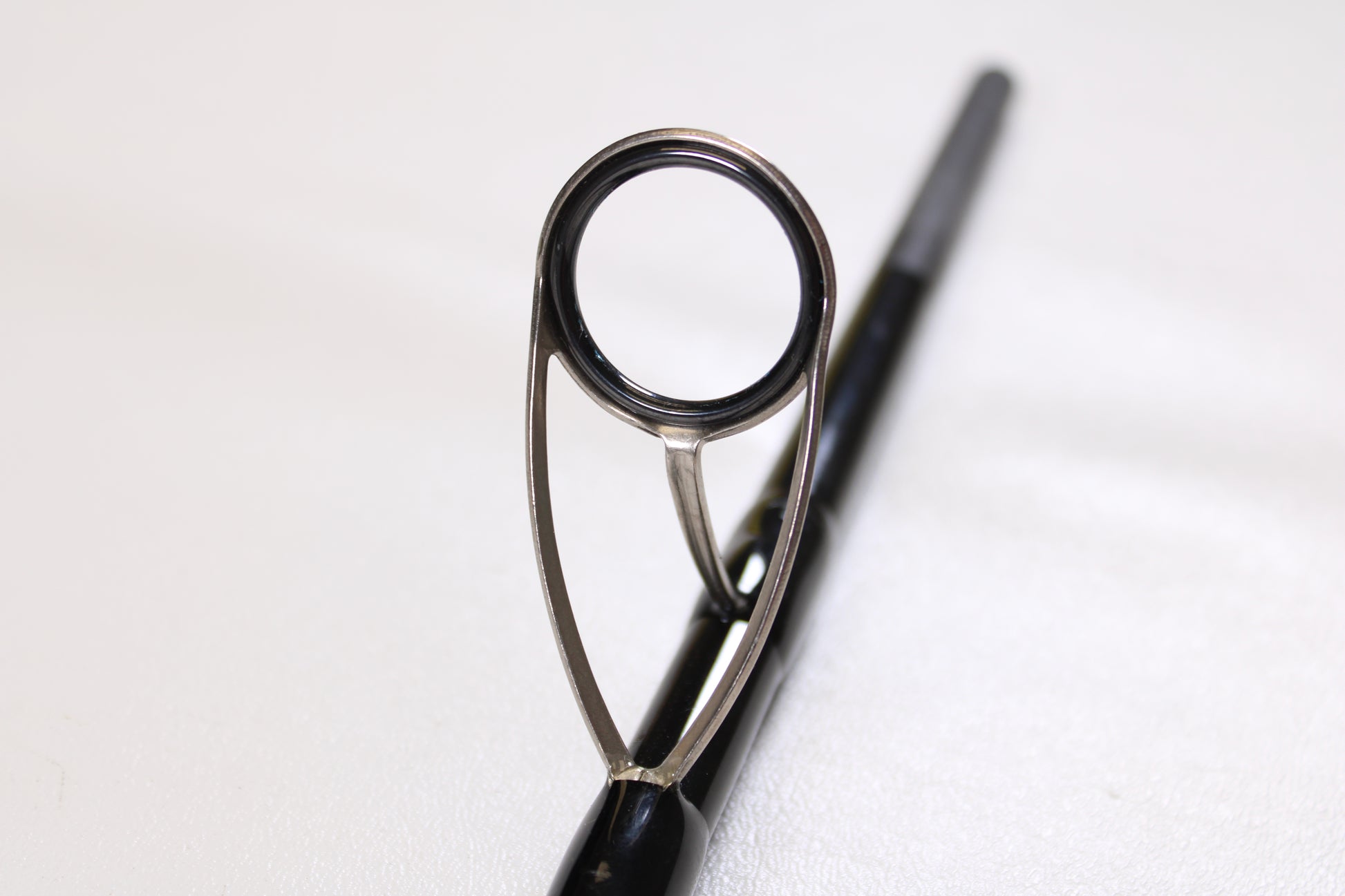 Close-up of the metal guide ring on a Century SlingShot SS 1265 10'6" 2 Piece Used Spinning Rod in excellent condition, with the rod extending out of focus—ideal for highlighting quality gear in our Century trade-ins.