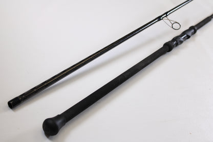 Two black Century SurfMachine SM10L 10'0" 30/70 split used spinning rod sections lie parallel on a white surface. Part of our Rod and Reel Trade-In Program, it includes a handle with reel seat and guide ring—excellent condition.