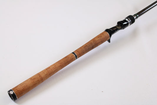 The Megabass Orochi XX F6-711XXG Launcher 7'11" Used Casting Rod in excellent condition features a cork handle and black reel seat, shown on a white background. Trade in your gear for store credit and maximize value.