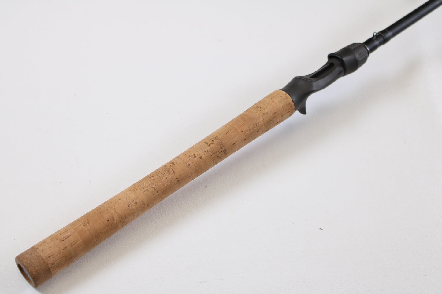 A close-up of a Daiwa Kage KAG761HRB-G Deep Crank 7'6" Heavy casting rod handle, featuring a cork grip and black reel seat—ideal for our trade-in program where you can earn store credit on used Daiwa rods in excellent condition.