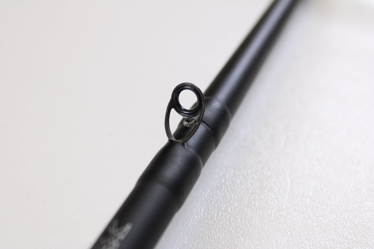 A close-up of the Daiwa Kage KAG761HRB-G Deep Crank 7'6" Heavy used casting rod in excellent condition, focusing on a single line guide against a blurred white background—ideal for anglers considering gear trade-ins.