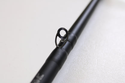 A close-up of the Daiwa Kage KAG761HRB-G Deep Crank 7'6" Heavy used casting rod in excellent condition, focusing on a single line guide against a blurred white background—ideal for anglers considering gear trade-ins.