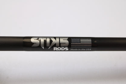A close-up of a black Stik5 Elevate Series The One 7'3" Medium Heavy casting rod in excellent used condition, labeled "Stik5," with an American flag and "Made in the USA"—eligible for our trade-in program to earn store credit.