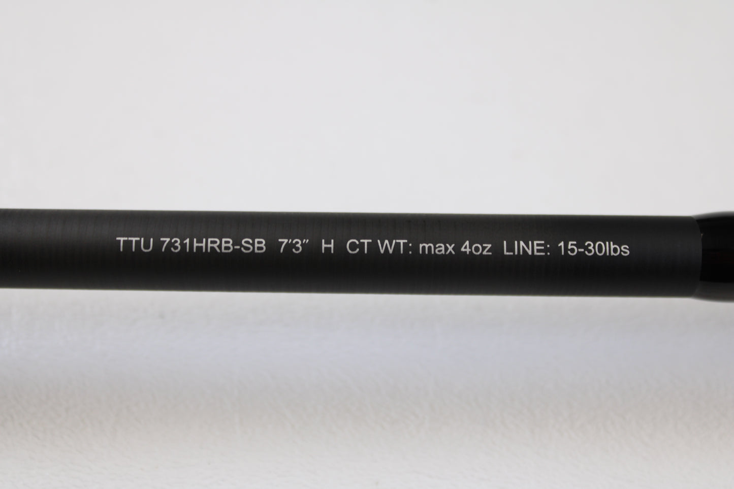 Close-up of a Daiwa Tatula TTU 731HRB-SB 7'3" Heavy Swimbait Used Casting Rod (mint condition) with white spec text on a black rod, against plain white background—eligible for our Rod and Reel Trade-In Program for store credit.