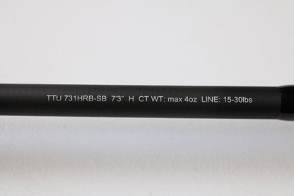 Close-up of a Daiwa Tatula TTU 731HRB-SB 7'3" Heavy Swimbait Used Casting Rod (mint condition) with white spec text on a black rod, against plain white background—eligible for our Rod and Reel Trade-In Program for store credit.