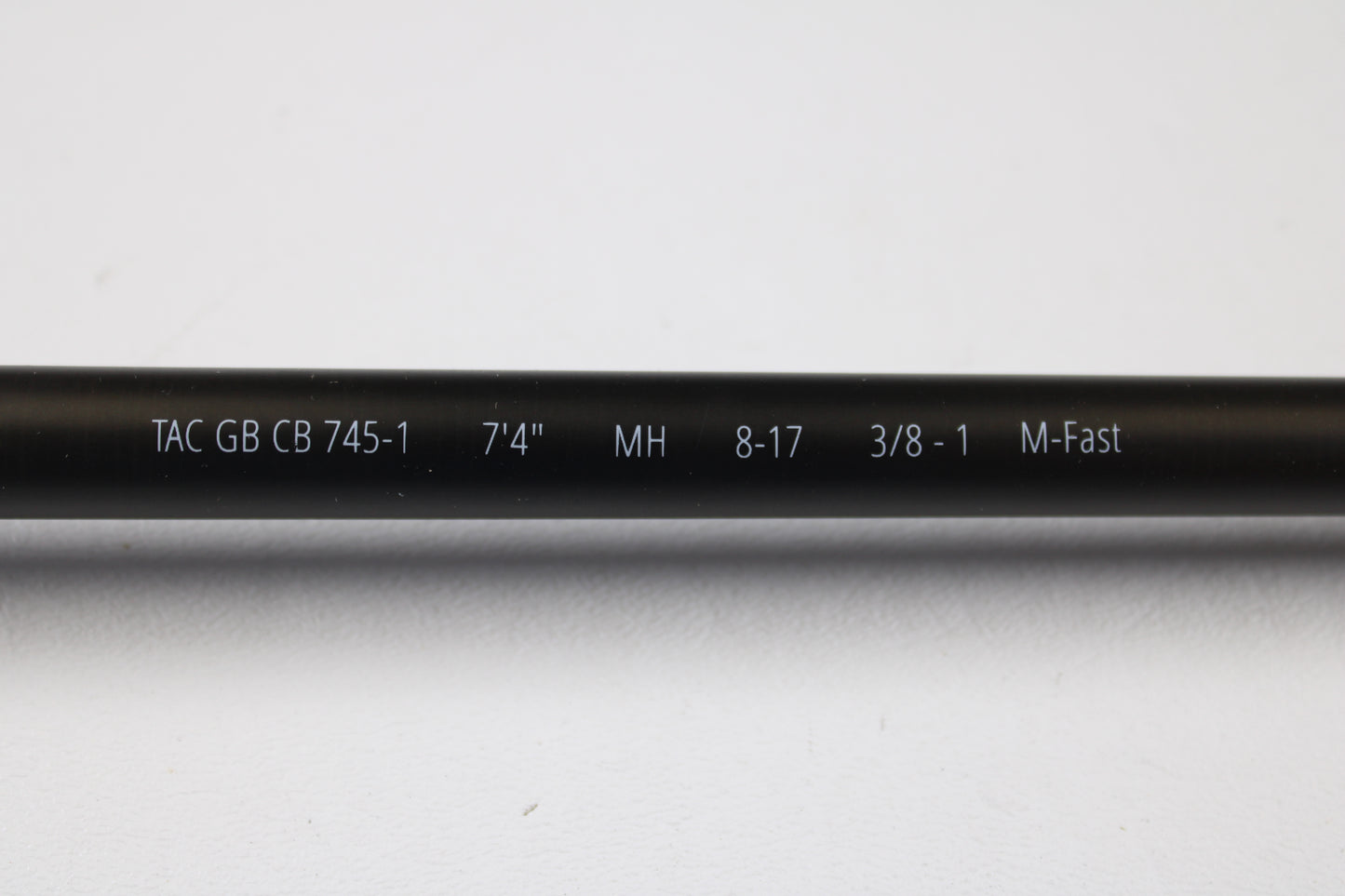 A close-up of a Temple Fork TFO Tactical Glass Bass TACGBCB745-1 7'4" Medium Heavy Used Casting Rod in excellent condition displays its white specs for easy ID as part of our Rod and Reel Trade-In Program.