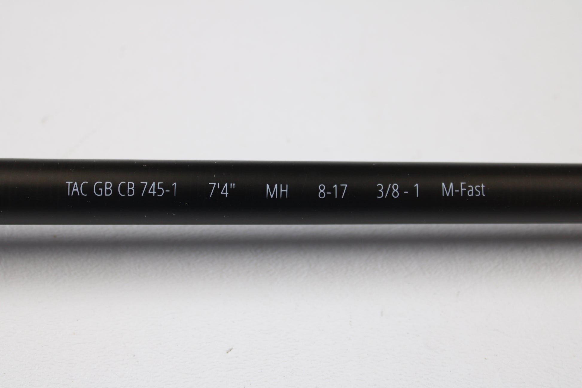 A close-up of a Temple Fork TFO Tactical Glass Bass TACGBCB745-1 7'4" Medium Heavy Used Casting Rod in excellent condition displays its white specs for easy ID as part of our Rod and Reel Trade-In Program.