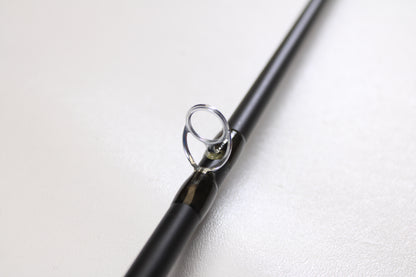 Close-up of a Temple Fork TFO Tactical Bass TACMBR734-1 7'3" Medium Used Casting Rod in excellent condition, showing the shiny metal guide on a black rod—ideal for those considering our rod and reel trade-in program.