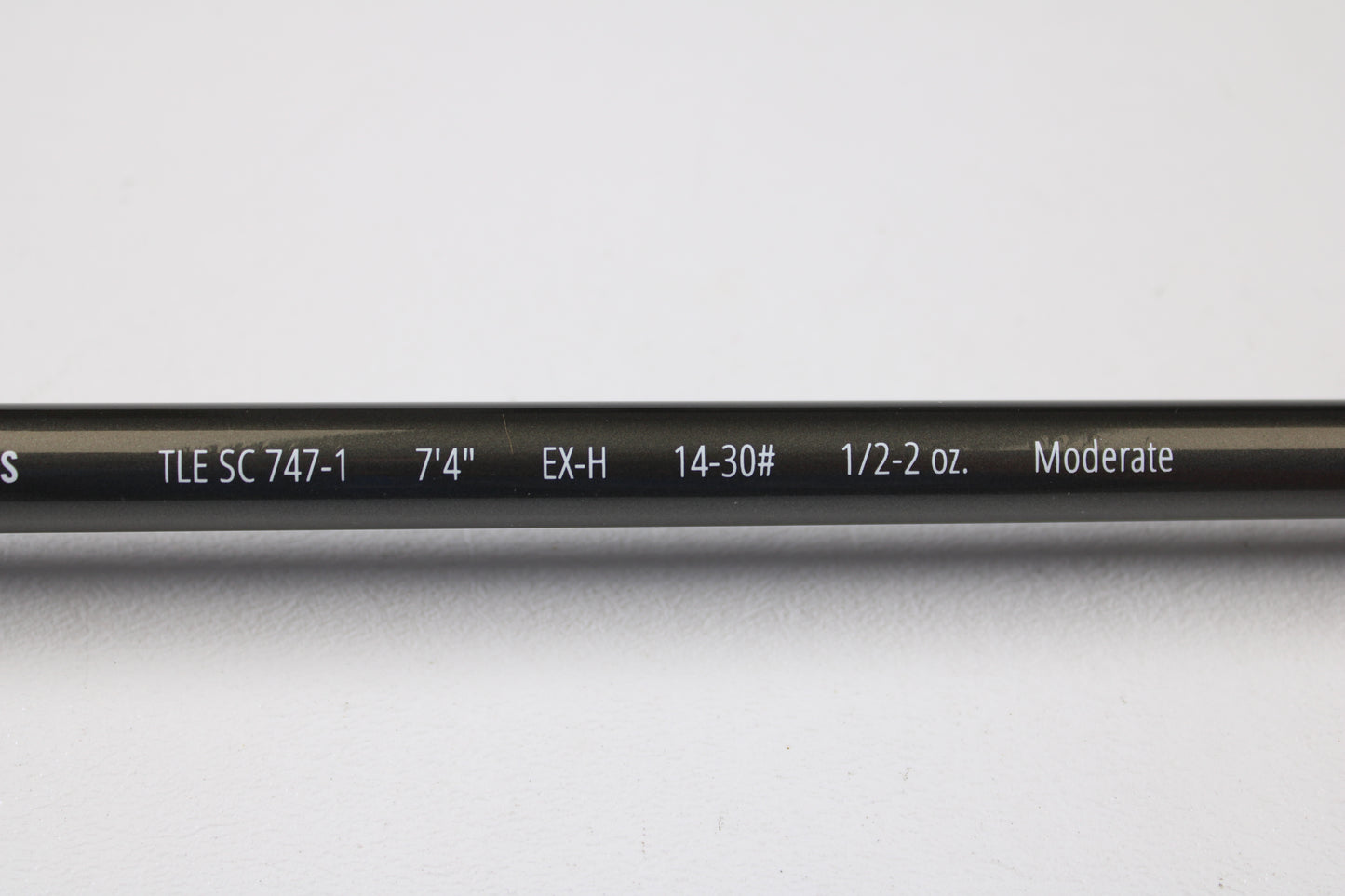 A close-up of a Temple Fork TFO Tactical Elite Bass TLE SC 747-1 7'4" Ex-Heavy used casting rod (excellent condition) shows its specs on the blank. This gear is part of our rod and reel trade-in program, displayed on a white background.