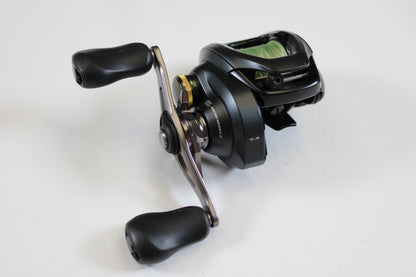 A Shimano Curado 200 K CU200HGK 7.4:1 RH used casting reel in excellent condition with dual ergonomic handles and metallic accents is displayed on a white surface—upgrade or shop quality used Shimano gear today.
