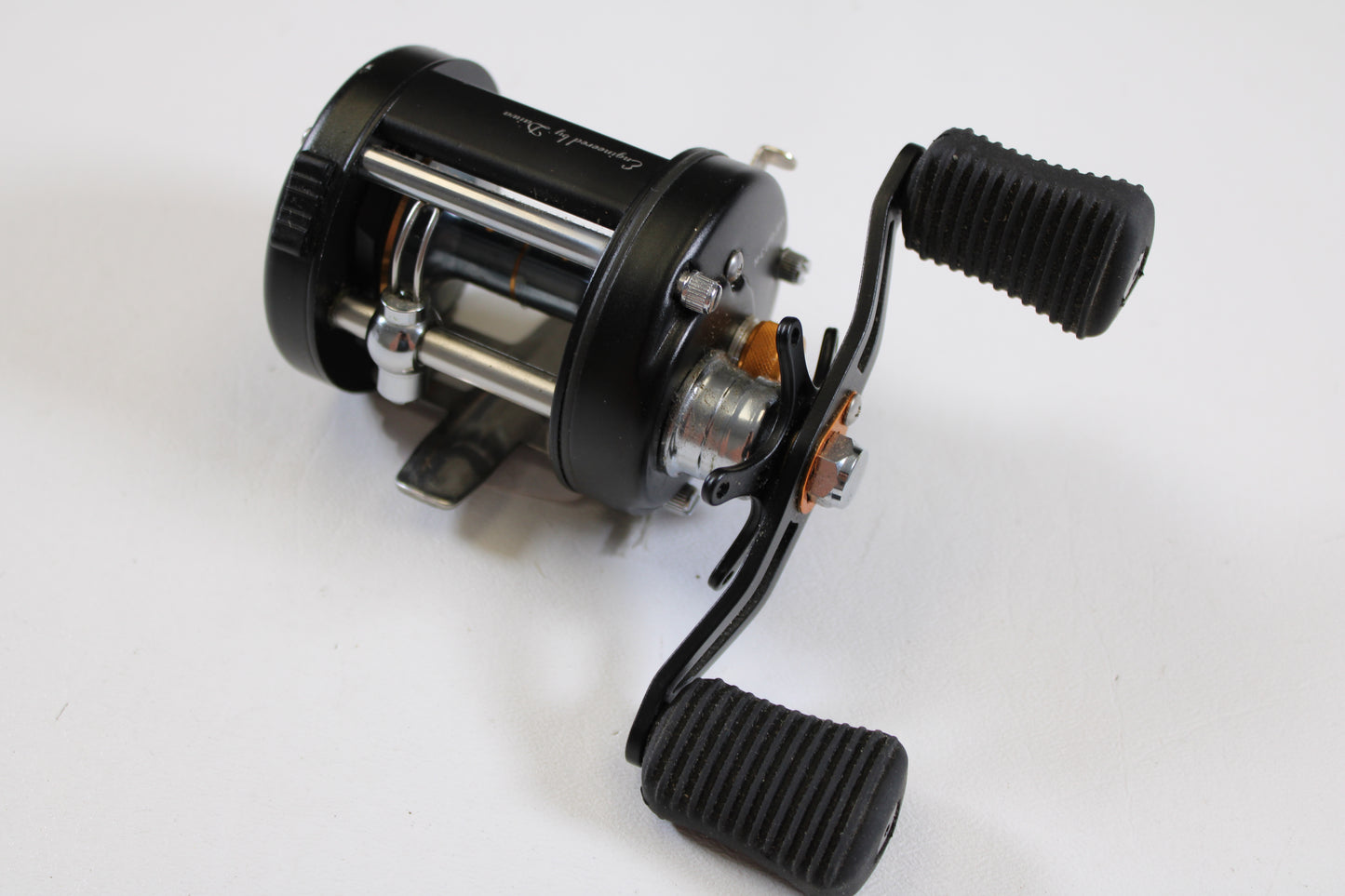 A close-up of the Daiwa Millionaire Classic UTD M-CUTD250L 5.1:1 LH Used Casting Reel in good condition, featuring two ribbed handles and a silver spool—ideal for upgrading or shopping pre-owned Daiwa gear.