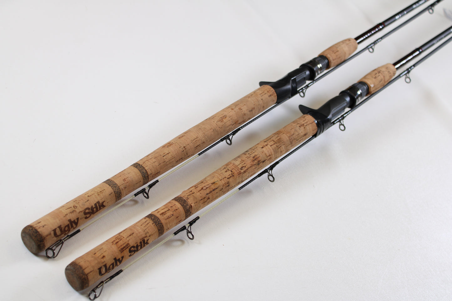 Two Shakespeare Ugly Stik Elite Salmon/Steelhead 8'6" medium used casting rods in excellent condition are side by side, ready for our Rod and Reel Trade-In Program—trade your gear for store credit toward your next upgrade.