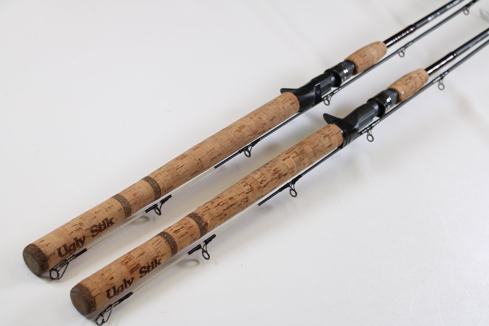 Two Shakespeare Ugly Stik Elite Salmon/Steelhead 8'6" medium used casting rods in excellent condition are side by side, ready for our Rod and Reel Trade-In Program—trade your gear for store credit toward your next upgrade.