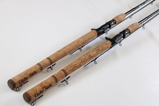 Two Shakespeare Ugly Stik Elite Salmon/Steelhead 8'6" medium used casting rods in excellent condition are side by side, ready for our Rod and Reel Trade-In Program—trade your gear for store credit toward your next upgrade.