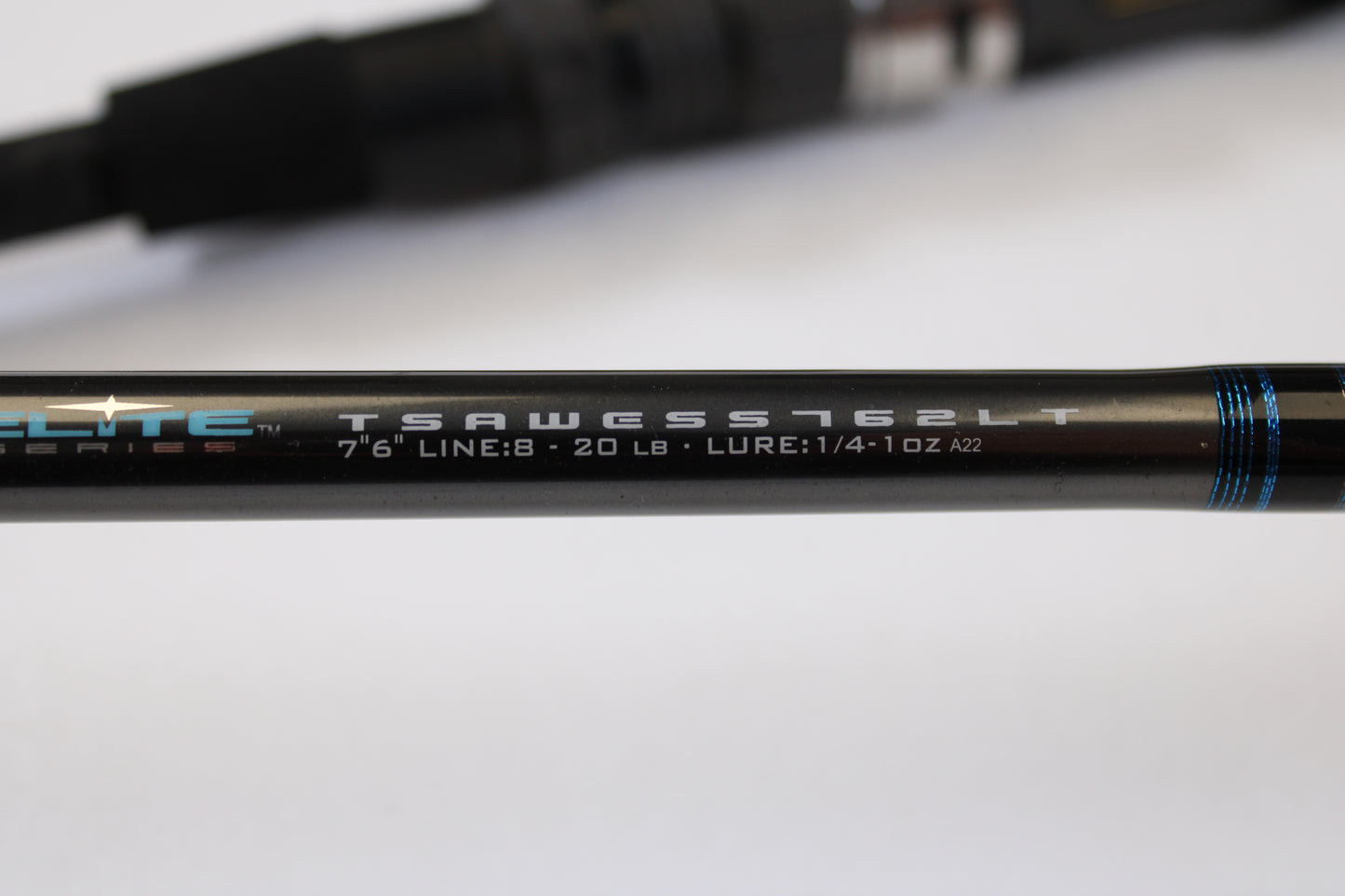 Close-up of the Tsunami Airwave Elite TSAWESS762LT 7'6" 2 Piece Used Spinning Rod in excellent condition—showing model details on a sleek black rod with blue accents. Perfect for rod and reel trade-ins or browsing quality used gear.