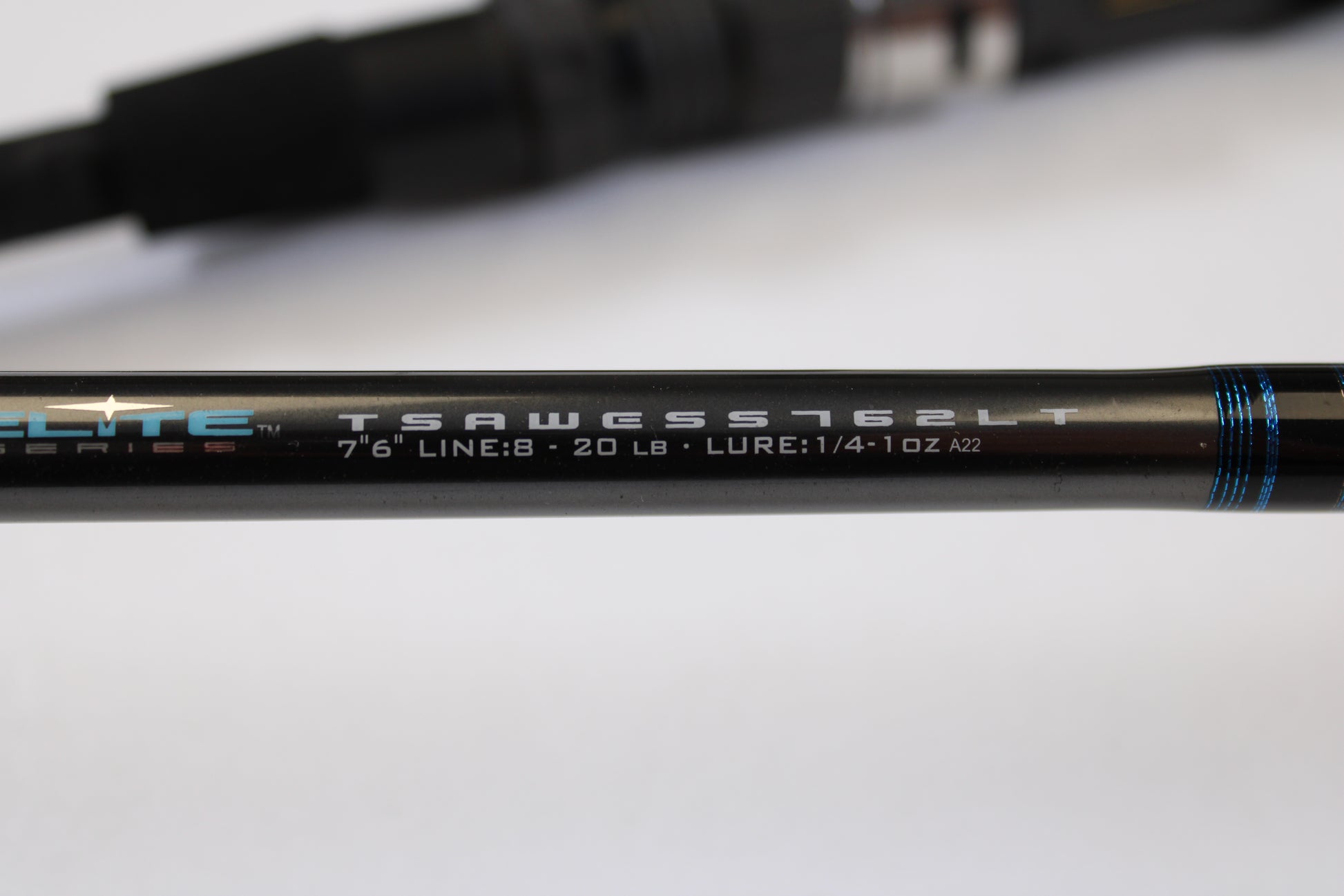 Close-up of the Tsunami Airwave Elite TSAWESS762LT 7'6" 2 Piece Used Spinning Rod in excellent condition—showing model details on a sleek black rod with blue accents. Perfect for rod and reel trade-ins or browsing quality used gear.