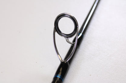 Close-up of the Tsunami Airwave Elite TSAWESS762LT 7'6" used spinning rod's guide, featuring a sturdy metal ring and frame on its black rod—ideal for anyone shopping quality pre-owned fishing gear.