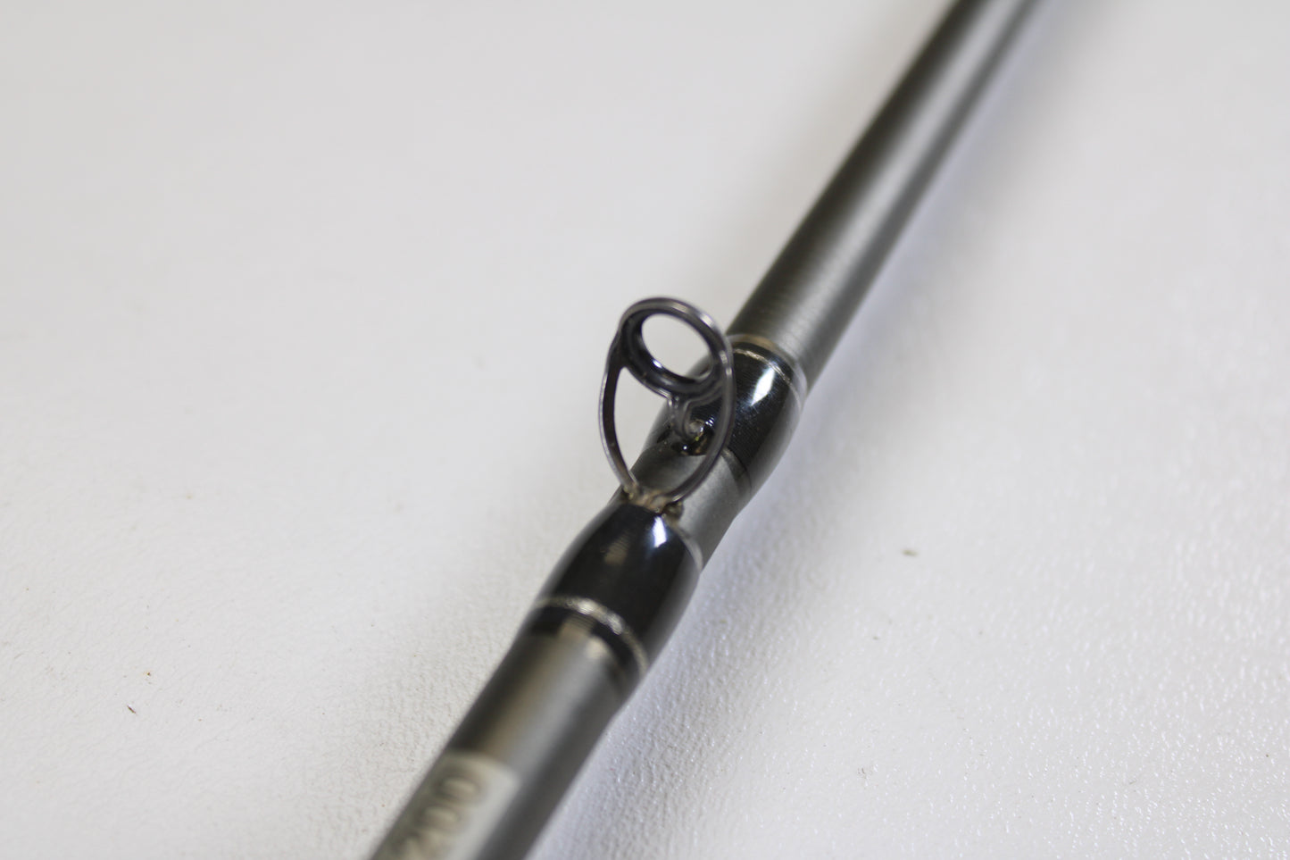 Close-up of the Fenwick Elite Bass ELTB70MH-FC 7'0" Medium Heavy Casting Rod (Used, Very Good Condition) guide ring on a grey rod, set against a white background—ideal for those upgrading with our Trade-In Program.