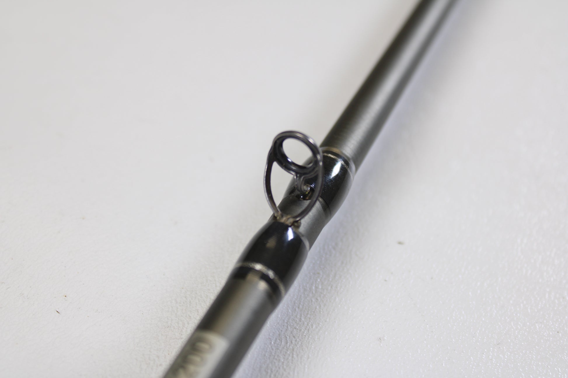 Close-up of the Fenwick Elite Bass ELTB70MH-FC 7'0" Medium Heavy Casting Rod (Used, Very Good Condition) guide ring on a grey rod, set against a white background—ideal for those upgrading with our Trade-In Program.