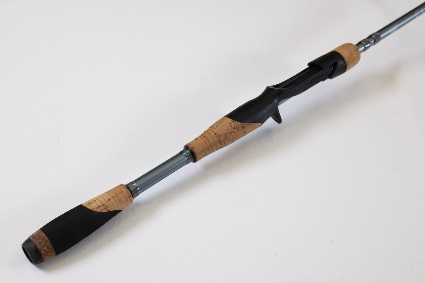 A close-up of the Fenwick Elite Bass ELB610MH-FC 6'10" Medium Heavy used casting rod, featuring a cork grip, black reel seat, and silver shaft—ideal for anglers considering our rod and reel trade-in program.