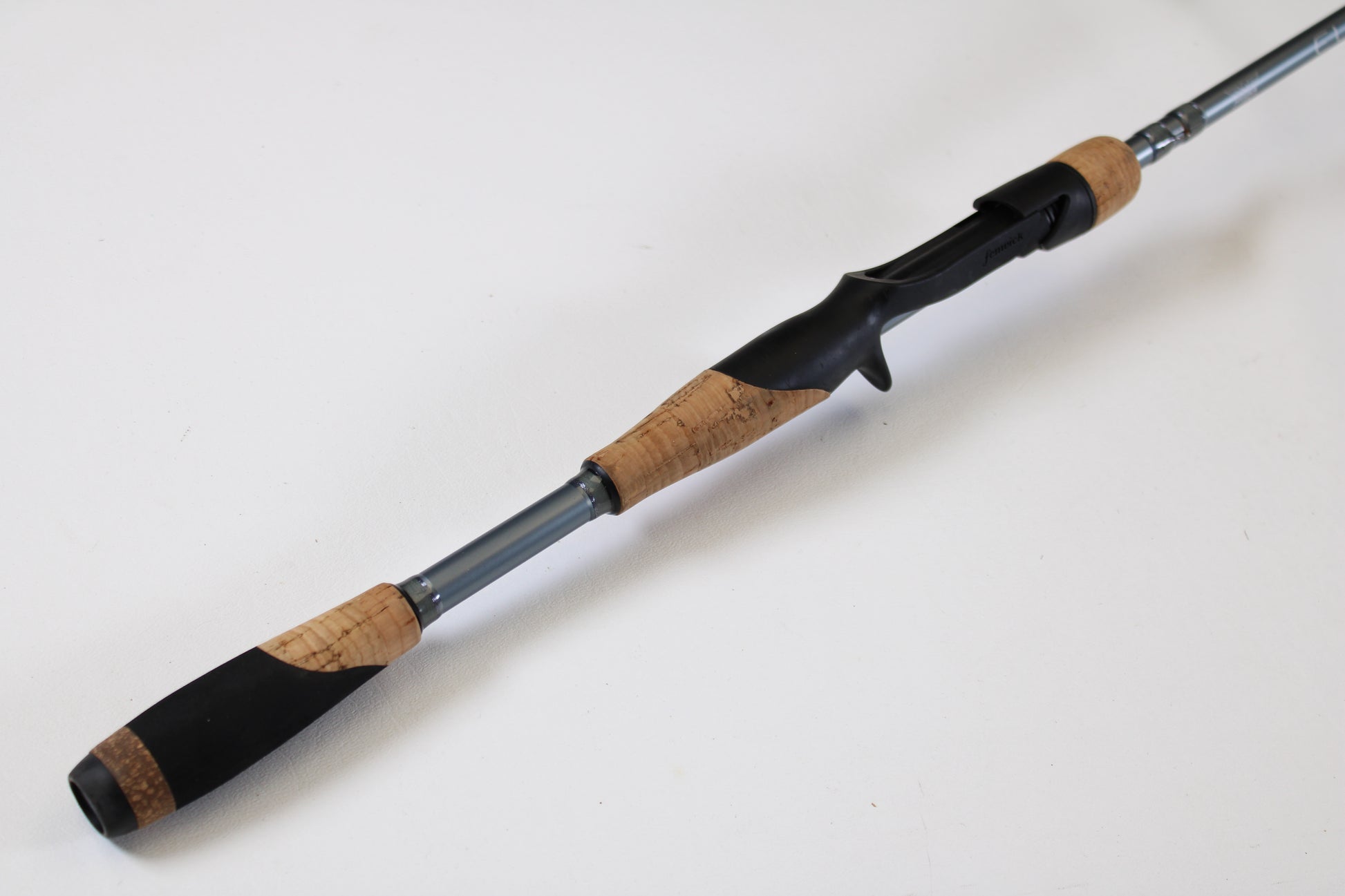 A close-up of the Fenwick Elite Bass ELB610MH-FC 6'10" Medium Heavy used casting rod, featuring a cork grip, black reel seat, and silver shaft—ideal for anglers considering our rod and reel trade-in program.