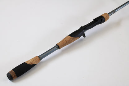 A close-up of the Fenwick Elite Bass ELB610MH-FC 6'10" Medium Heavy used casting rod, featuring a cork grip, black reel seat, and silver shaft—ideal for anglers considering our rod and reel trade-in program.