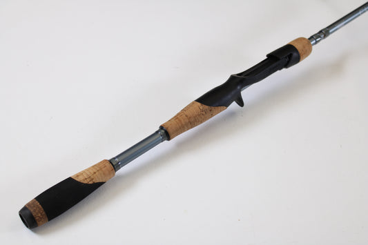 A close-up of the Fenwick Elite Bass ELB610MH-FC 6'10" Medium Heavy used casting rod, featuring a cork grip, black reel seat, and silver shaft—ideal for anglers considering our rod and reel trade-in program.