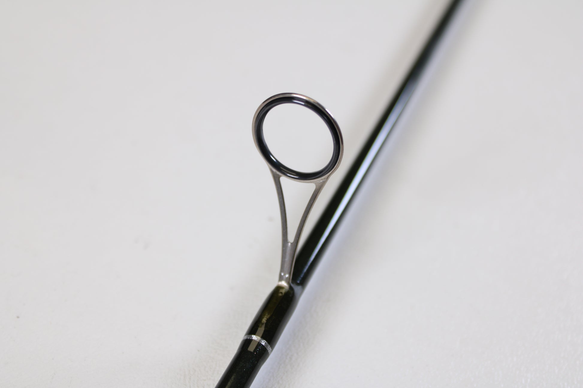 A close-up of the St. Croix Legend Elite Panfish LEP69LF 6'9" Light used spinning rod highlights a guide ring on its glossy black surface—promoting our Rod and Reel Trade-In Program: turn your used gear into store credit. Shot on a plain white background.