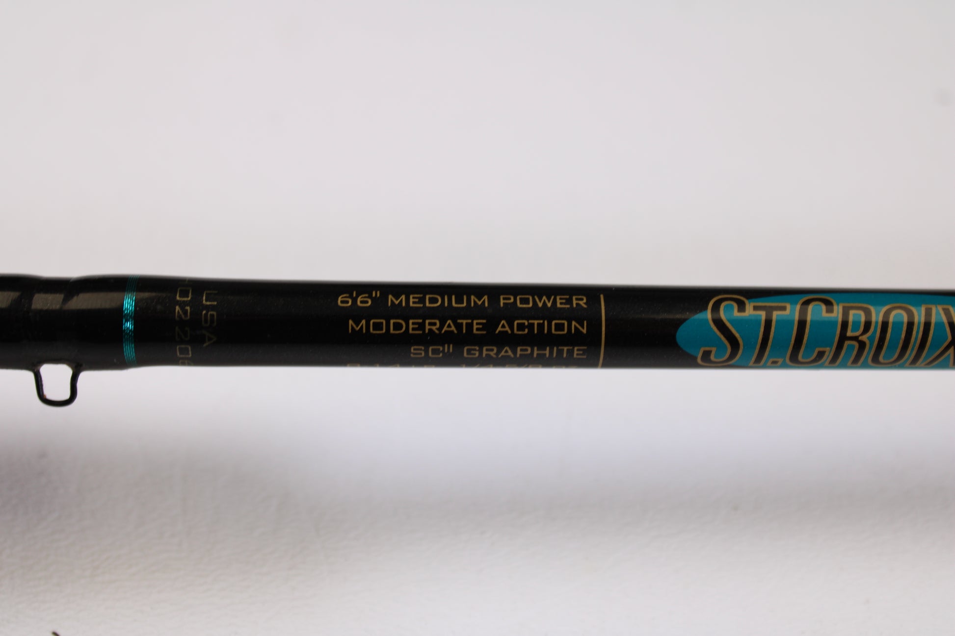 A close-up of a St. Croix Premier Crankbait PC66MM 6'6" Medium used casting rod in very good condition, showing its details on a black background with gold and teal accents—ideal for our Rod and Reel Trade-In Program.