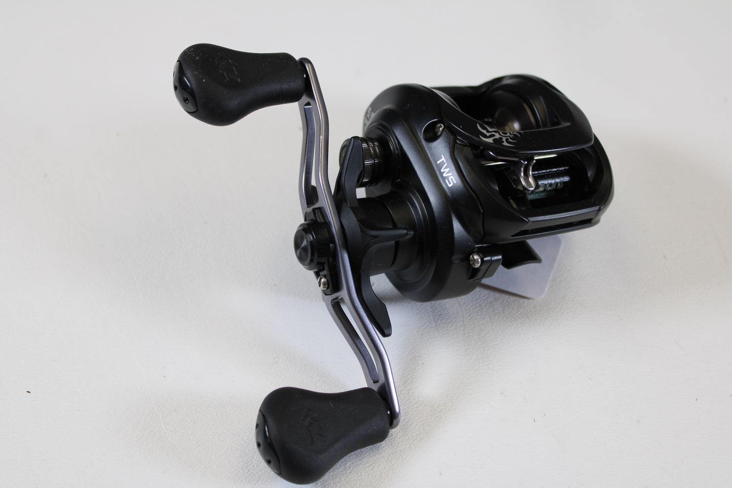 A Daiwa Tatula 150 TAT150P 5.5:1 RH used casting reel in excellent condition, with a sleek black dual-handle design, is perfect for trading in through our Rod and Reel Trade-In Program for store credit.