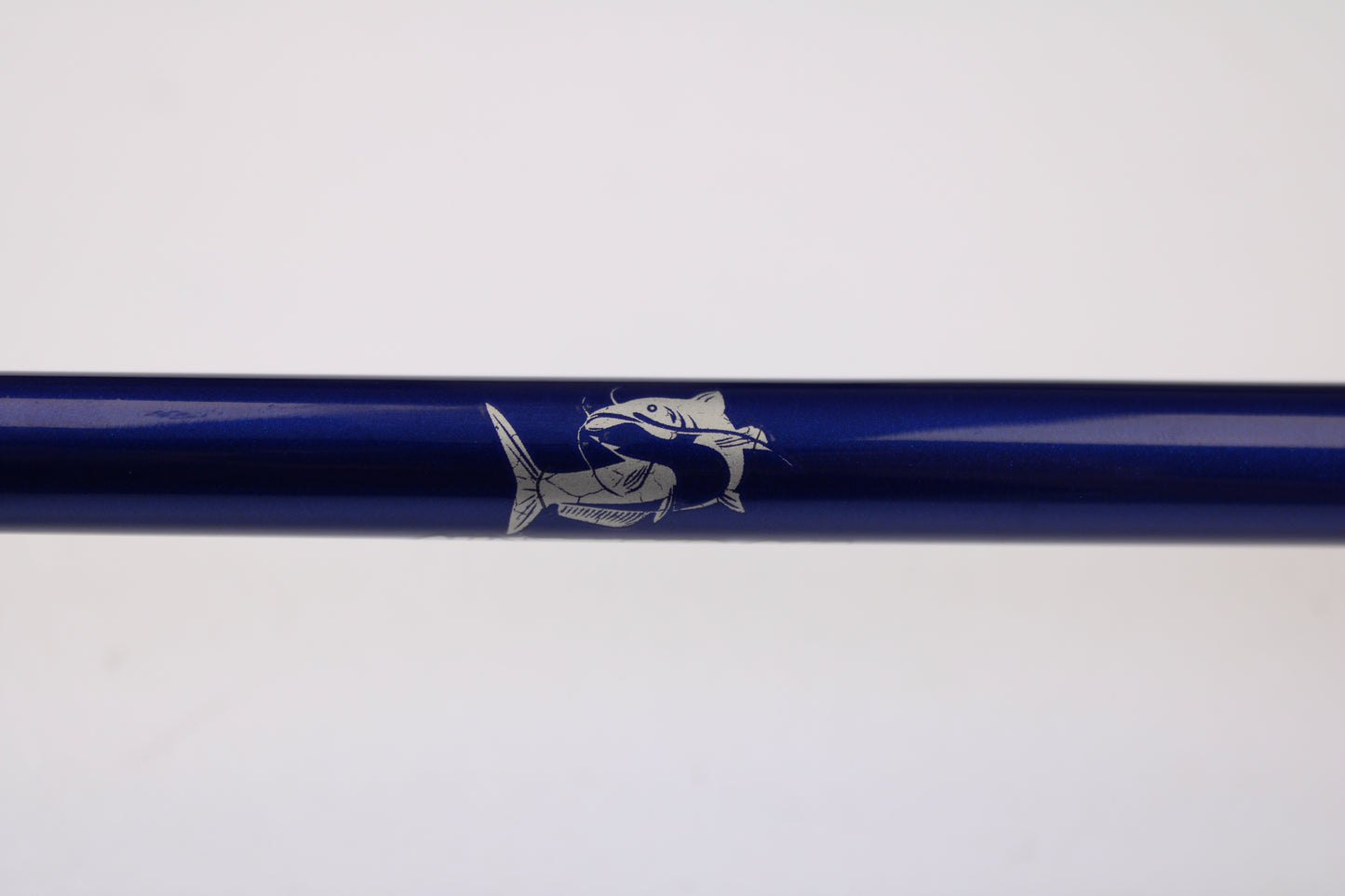 A close-up of the Shattered Cat 7'6" Heavy Used Casting Rod in excellent condition, featuring a white fish illustration on its blue surface—ideal for the Rod and Reel Trade-In Program or upgrading your gear.