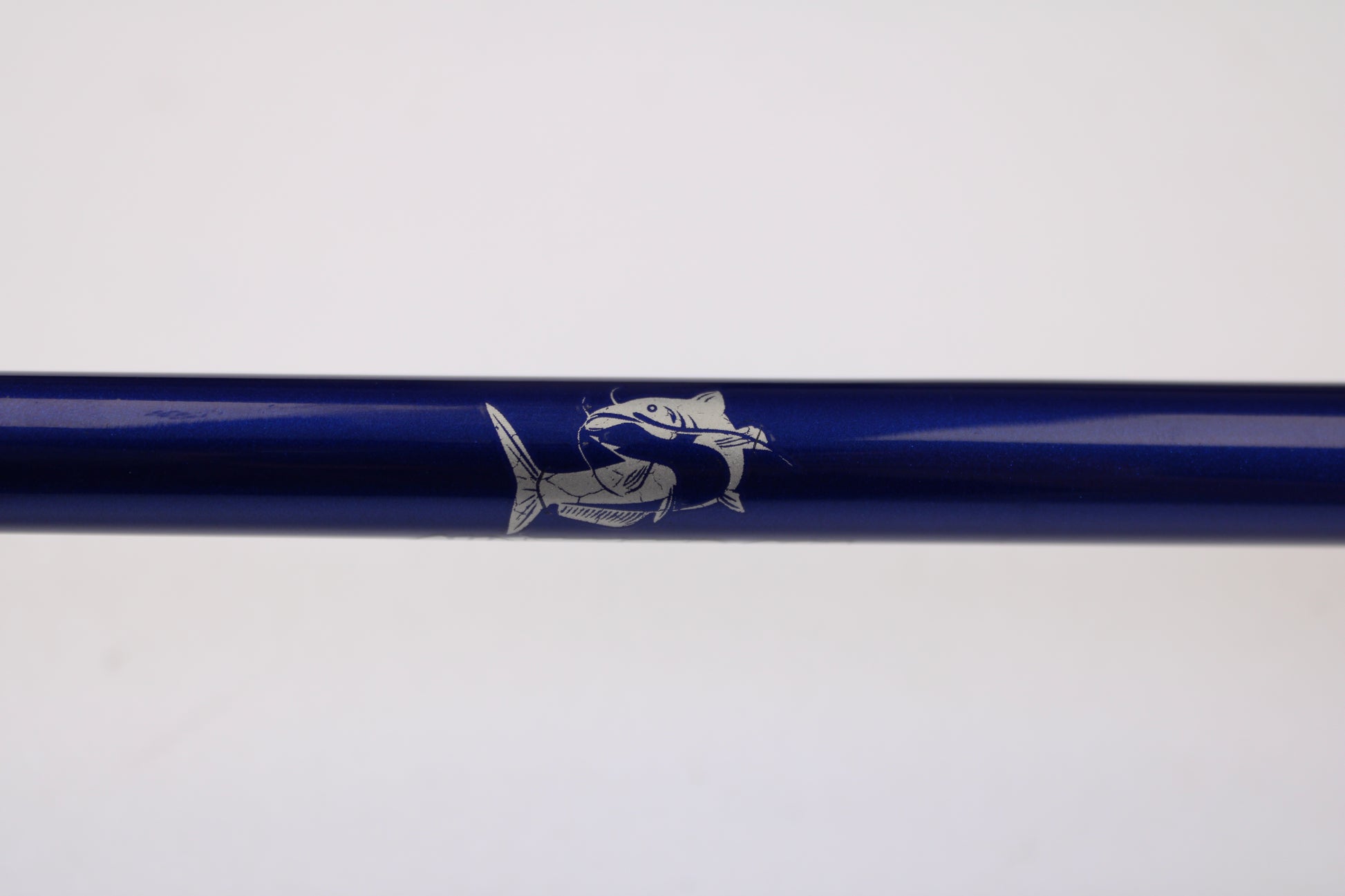 A close-up of the Shattered Cat 7'6" Heavy Used Casting Rod in excellent condition, featuring a white fish illustration on its blue surface—ideal for the Rod and Reel Trade-In Program or upgrading your gear.