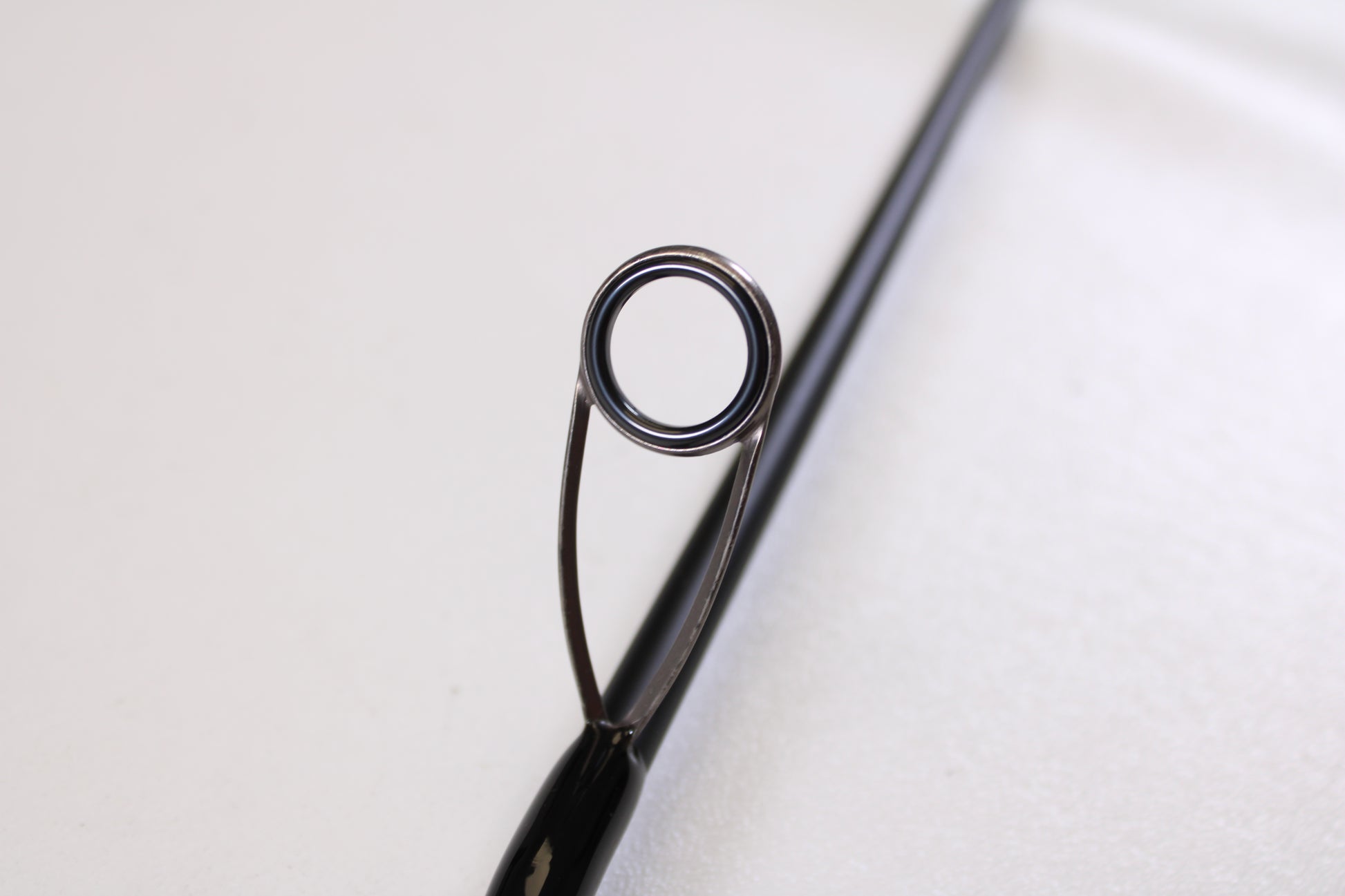 Close-up of the Airrus Stargate ASG681LF-S 6'8" Light Used Spinning Rod’s tip and metal guide ring against a white background—ideal for those looking to trade in or upgrade fishing gear for store credit.