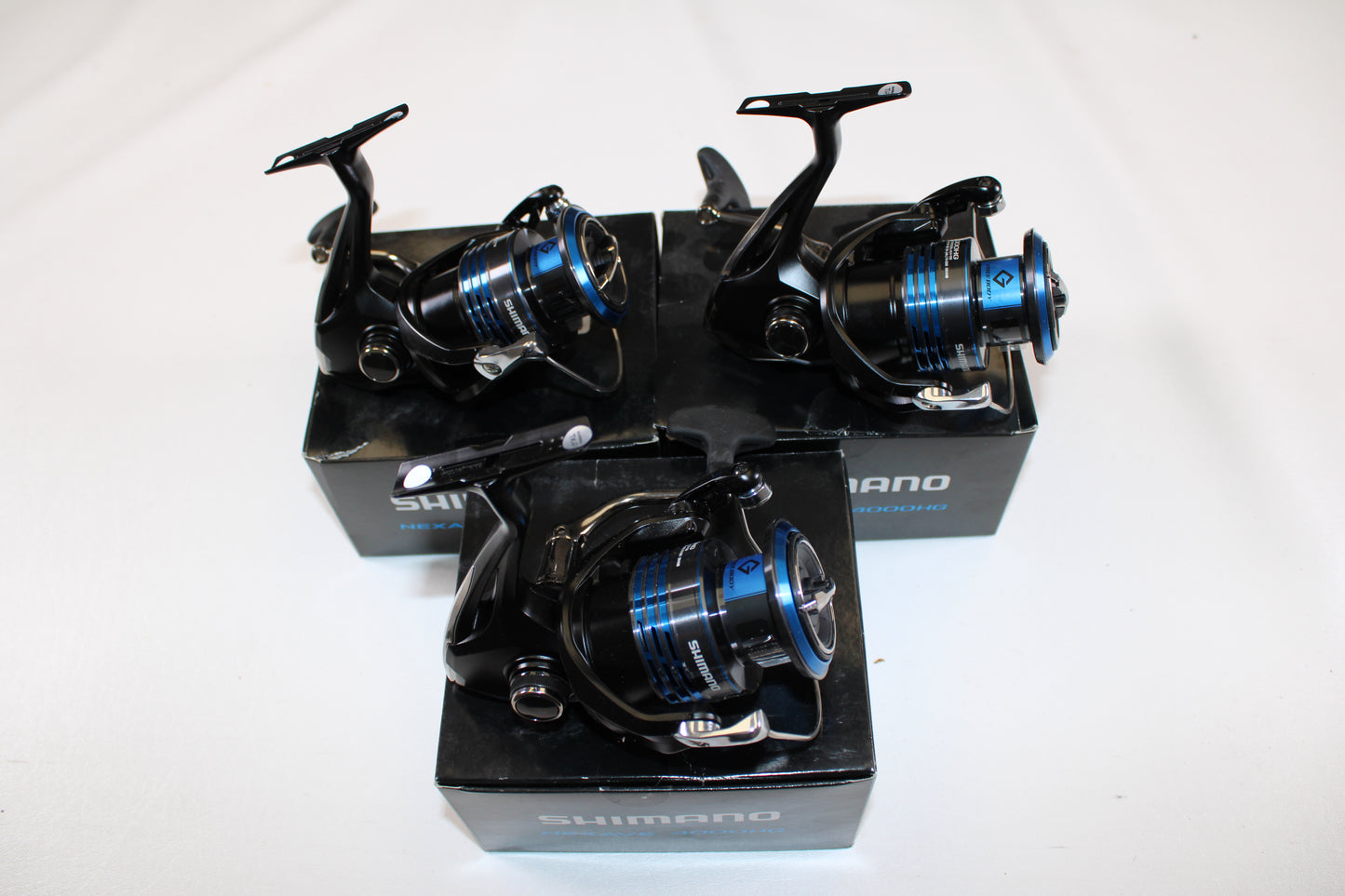 Three used Shimano Nexave 4000HGFI spinning reels in mint condition are shown atop their black boxes against a plain white background.