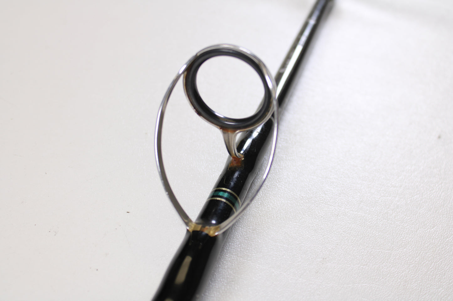 A close-up of the Cousins Tackle CLB 70L-S 7'0" spinning rod guide ring, showing the metal loop on the black rod—ideal for displaying these Qty: 3 used rods in very good condition for a Rod and Reel Trade-In program.