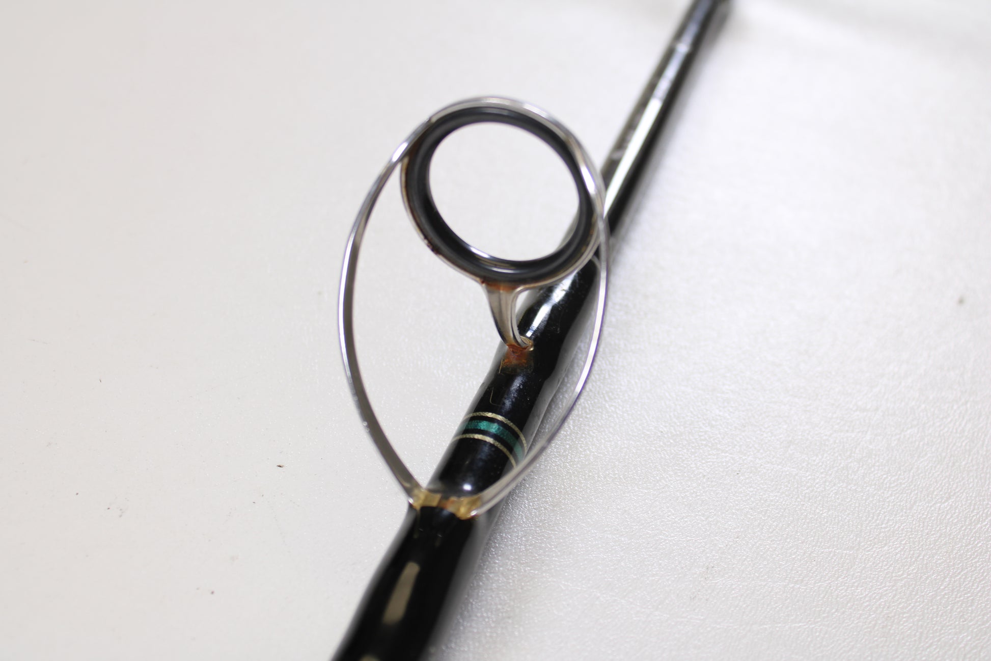 A close-up of the Cousins Tackle CLB 70L-S 7'0" spinning rod guide ring, showing the metal loop on the black rod—ideal for displaying these Qty: 3 used rods in very good condition for a Rod and Reel Trade-In program.