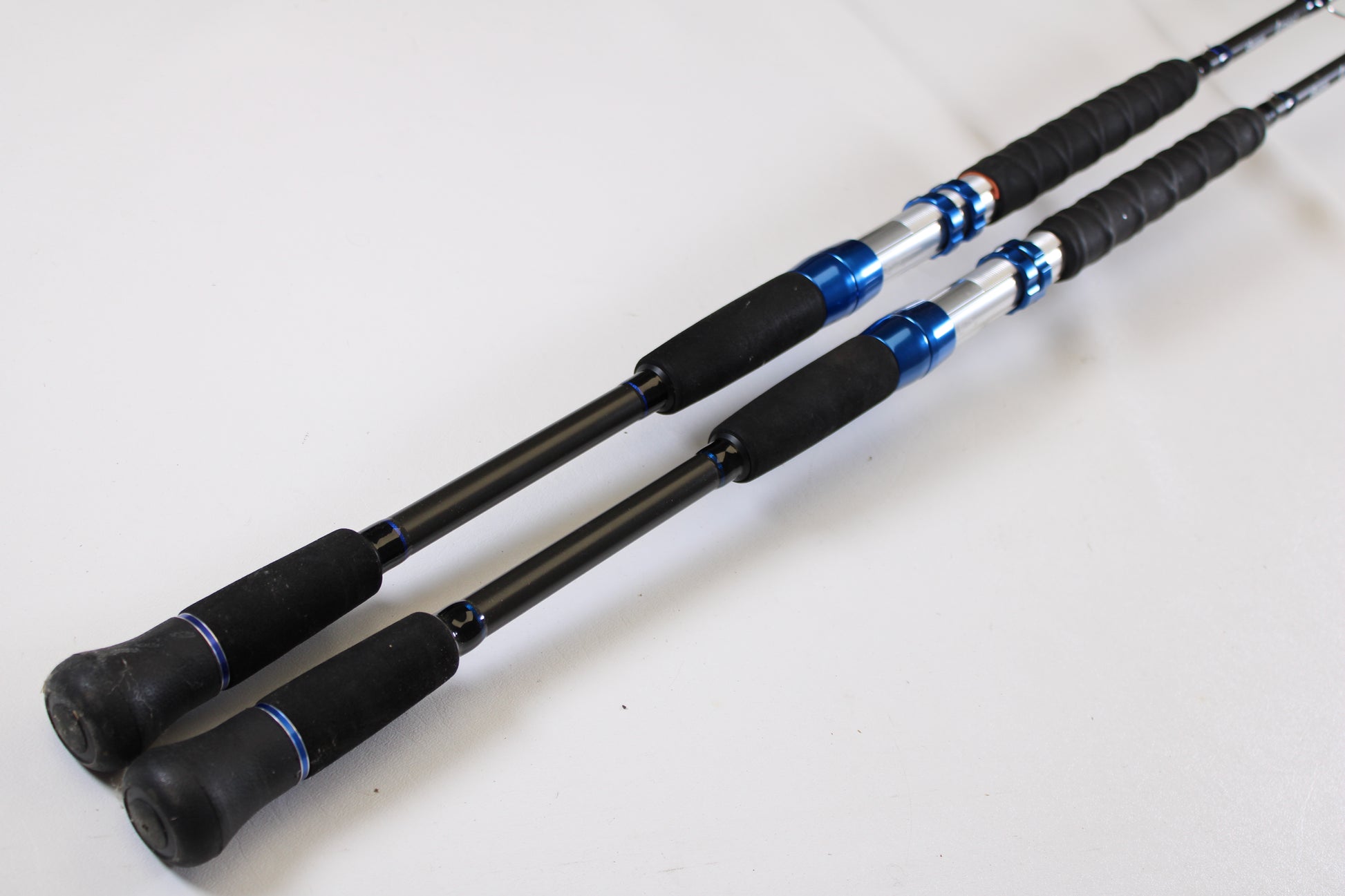 Two Okuma Cedros Jigging 6'6" Medium used casting rods (Qty: 2, excellent condition) are placed parallel on a white surface, ready for your next adventure or for our rod and reel trade-in program.