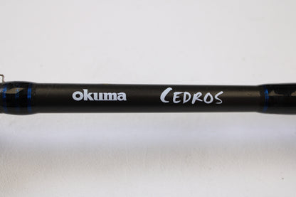 A close-up of an Okuma Cedros Jigging 6'6" Medium used casting rod in excellent condition. Qty: 2. Perfect for upgrading via our trade-in program or earning store credit for your used gear. Plain white background.
