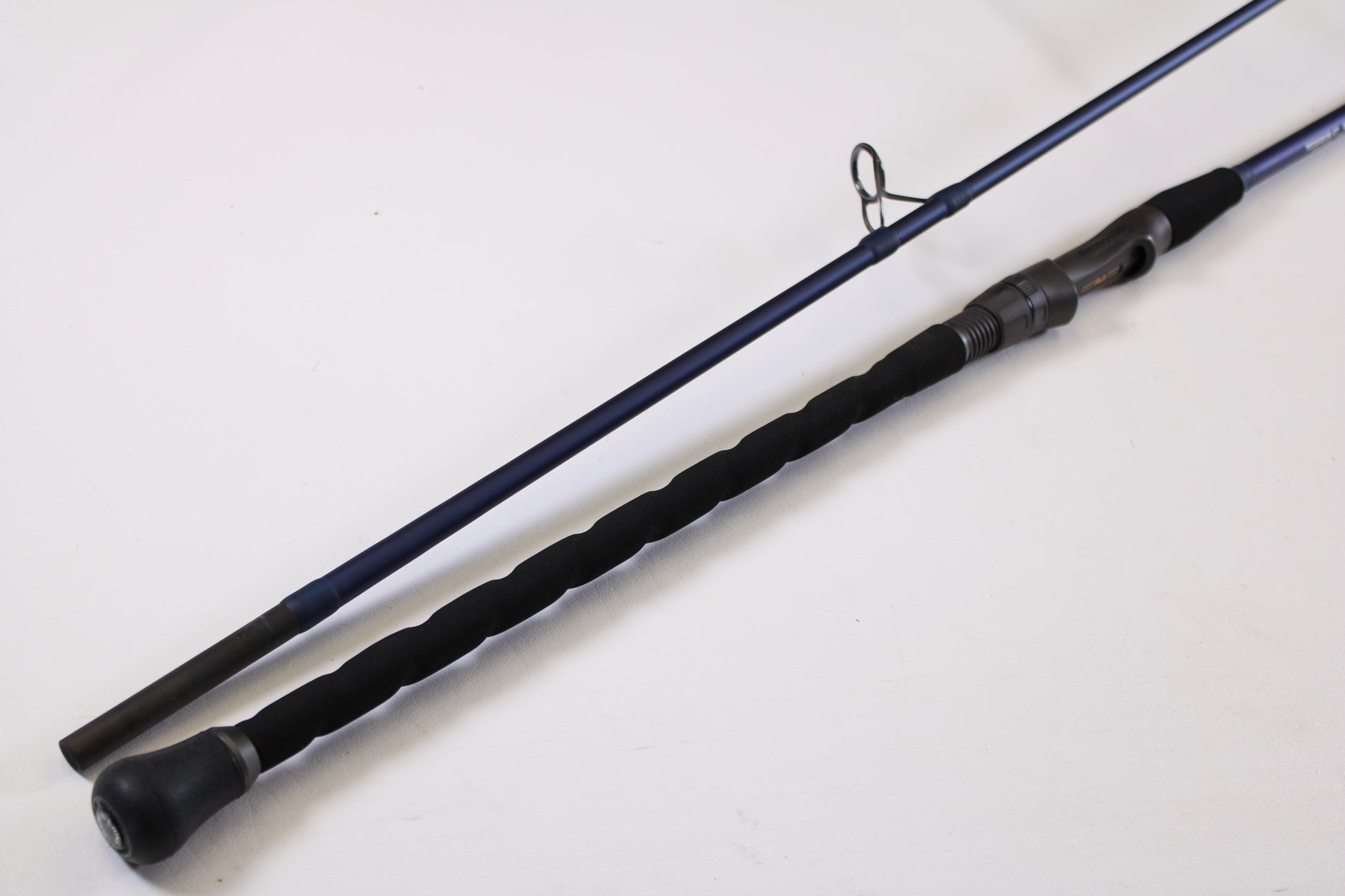 A close-up of the Tsunami SaltX Surf TSSTXIISS872M 8'7" Medium 2 Piece Used Spinning Rod—Excellent Condition—shows its black handle and reel seat, ideal for trading in through our Rod and Reel Trade-In Program for store credit.